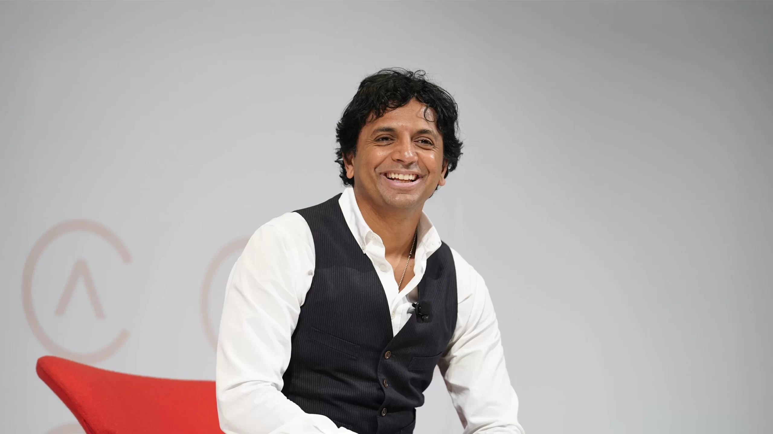 M Night Shyamalan sitting on stage